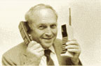 Photograph of a man holding an old and a new mobile phone.