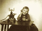 Photograph of a young boy talking on a telephone.