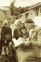 Photograph of old generation reading to young generation.